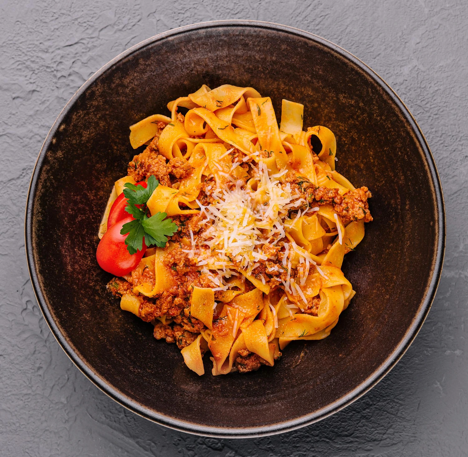 Plate of fettuccine bolognese garnished with basil and Parmesan, set in a cozy Italian kitchen.